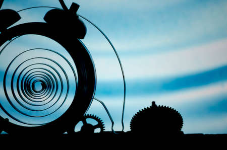 Broken alarm clock with springs and gears scattered on the background of bright light.の写真素材