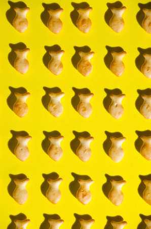 Cookies in form fish, yellow background, in bright sun with hard shadows.close up