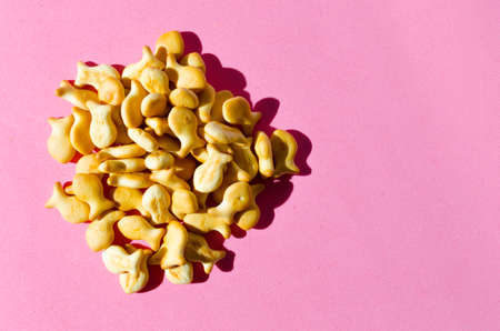 Cookies in form of fish on a pink background in bright light with hard shadows.Close up.