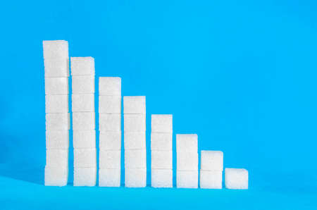 Sugar cubes in the form of an increasing scale on a blue backgroundの写真素材
