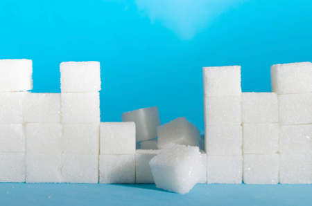 Destroyed wall of refined sugar cubes on blue background close-up.Protection and immunity.の写真素材
