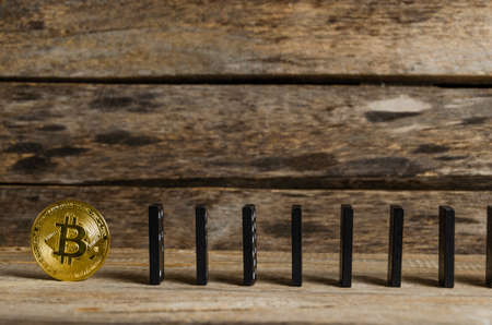 Domino and bitcoin coin on wooden background. Crash, Finance, inflation.