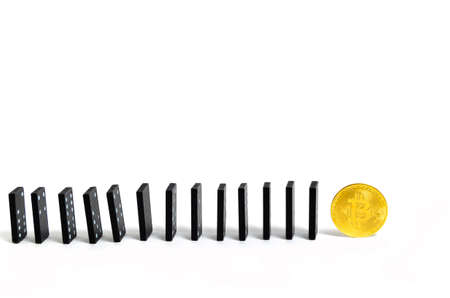 Dominoes knuckles opposite bitcoin coin on white background. Collapse and fall of cryptocurrency.の写真素材