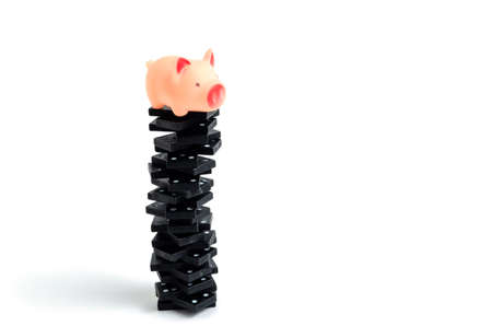 Pink, rubber pig on a tall pile of dominoes.の写真素材