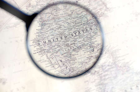 Old map with territory of United States of America and name of country is enlarged through a magnifying glass.の写真素材