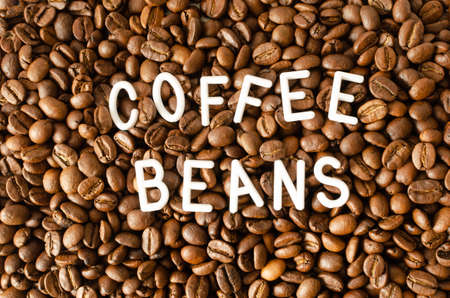 Background with coffee beans with white inscription in the middle.の写真素材