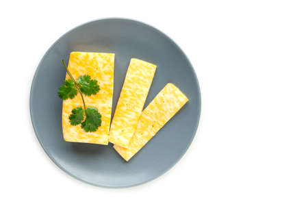 Sliced parsley cheese spread on a gray plate on a white background.の写真素材