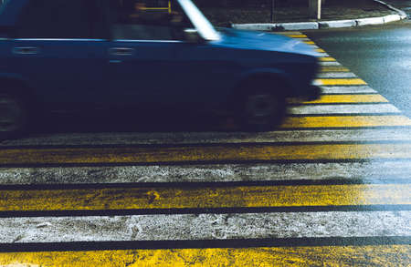 The car passes at high speed on a slippery wet in the rain pedestrian crossing.