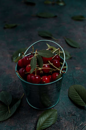Cherry berry in a small decorative bucket on the old village,concrete floor.