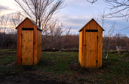 Two wooden, public toilets male and female, outdoors.