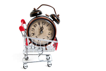 Retro alarm clock in shopping cart on white background.