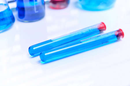 Vials of chemical blue liquid on a white laboratory tableの写真素材