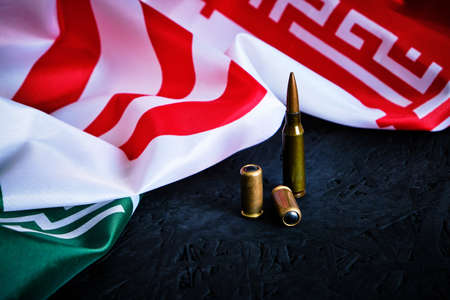 National flag of Iran on a dark background with bullets.