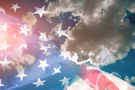 Flag of the United States of America against a background of blue sky and cloudsの写真素材