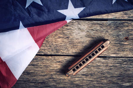 Flag of the United States of America and harmonica on a wooden background top view