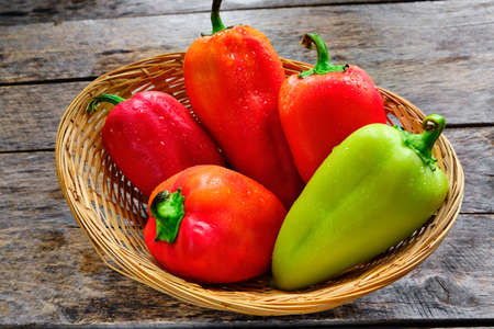 Bell peppers in a wicker basket on a rustic wooden tableの写真素材