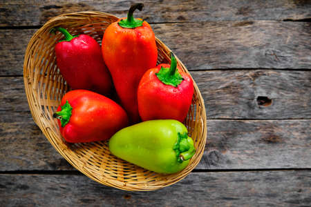 Bell peppers in a wicker basket on a rustic wooden table