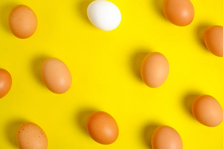 Chicken brown and white eggs on a yellow background