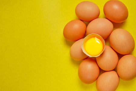 Chicken eggs on a yellow background with yolkの写真素材