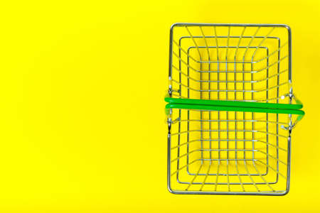 Metal basket on yellow background for shopping in supermarket, view from top.の写真素材
