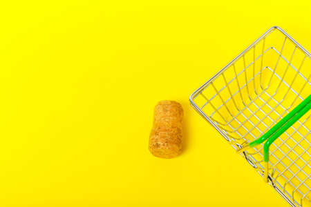 Wine stopper and shopping basket on yellow background