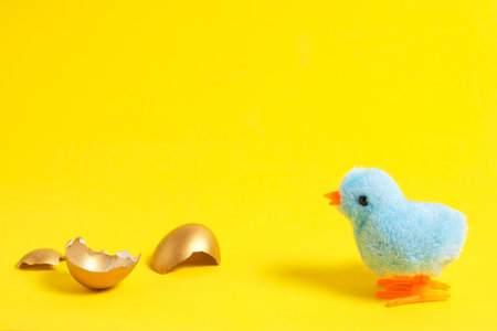 Blue chicken on a yellow background with a broken golden shellの写真素材