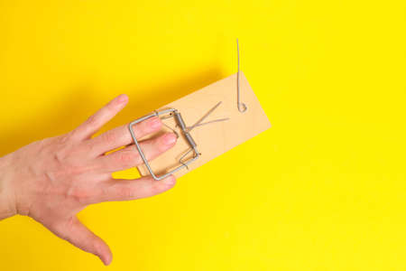 Man hand was caught in a mousetrap on a yellow background.Concept, risks, and failuresの写真素材
