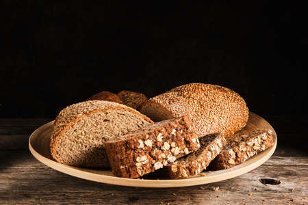 Sliced cereal bread and bread sprinkled with sesame seeds in a round plate
