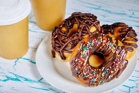 Chocolate donuts and takeaway coffee on a light backgroundの写真素材