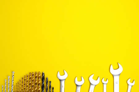 Set of drills and wrenches on a yellow background