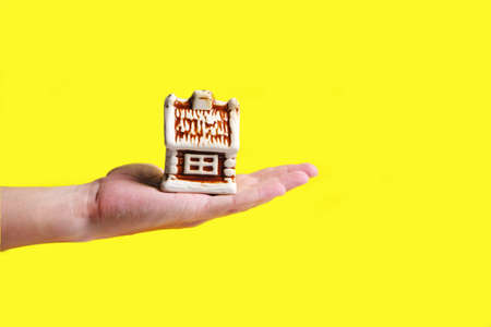 Toy house on palm of your hand on yellow background, mortgage sale or purchase of real estate, houses, apartmentsの写真素材