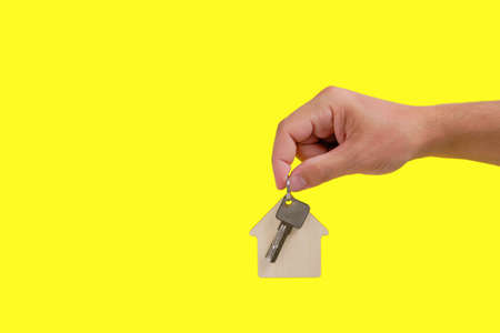 House keys with a keychain in hand on a yellow background