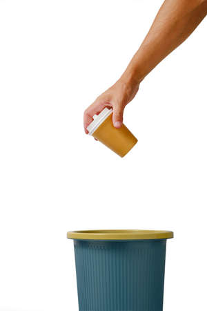 Hand on white background throws disposable cup of takeaway coffee into trash.Recycling and ecology