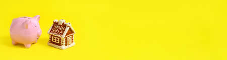 Banner, house and piggy bank on yellow background. Concept of mortgage and savings for housingの写真素材