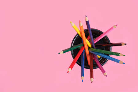 Office basket with colored pencils on a pink background