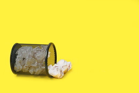 Rashes of crumpled paper from trash can, on yellow backgroundの写真素材