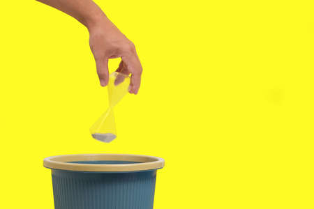 An hourglass is thrown into trash, yellow background.Concept of time loss, elapsed timeの写真素材