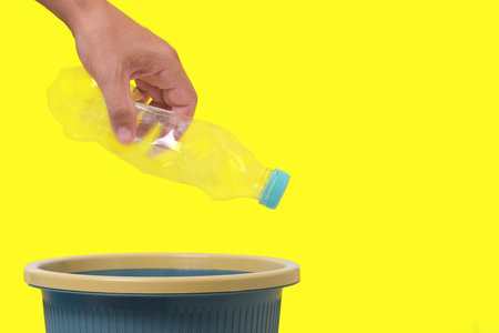 An empty plastic bottle in his hand is thrown into trashの写真素材