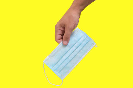 Protective medical mask in the hand on a yellow backgroundの写真素材