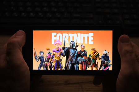 Kostanay, Kazakhstan, November 01, 2021. Man holding mobile phone with screensaver of popular game Fortnite 2 from Epic Gamesのeditorial素材