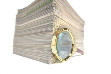 Stack of magazines and magnifying glass on white background.Concept of learning and pursuit of...