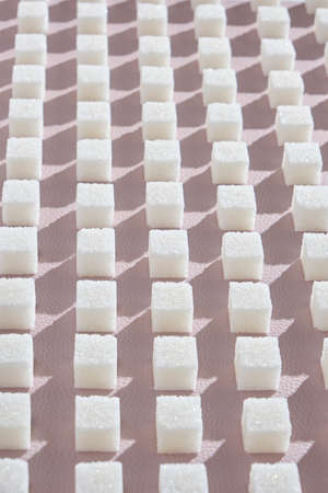 Refined sugar on pink background. Cubes of sweet and white sugar in geometricshape. Hard shadowsの写真素材