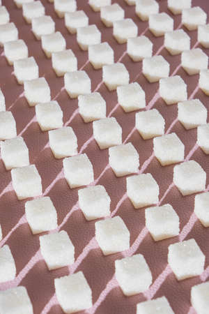 Refined sugar on pink background. Cubes of sweet and white sugar in geometricshape. Hard shadows
