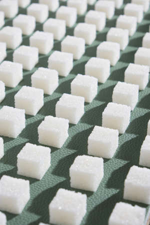 Refined sugar on green background. Cubes of sweet and white sugar in geometricshape. Hard shadowsの写真素材
