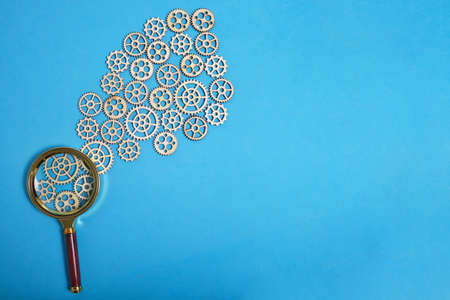 Magnifying glass and lot gears on blue background. Concept industry and education...