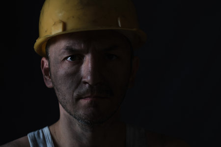 Portrait miner in helmet and undershirt with dirty faceの写真素材