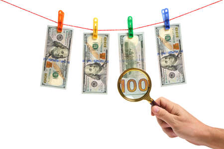Dollars are suspended by clothespins on white background and examined with a magnifying glassの写真素材