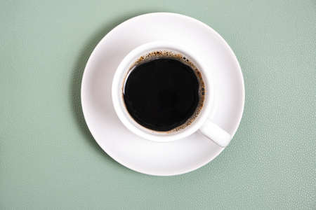 White cup with poured coffee, top view, on green backgroundの写真素材