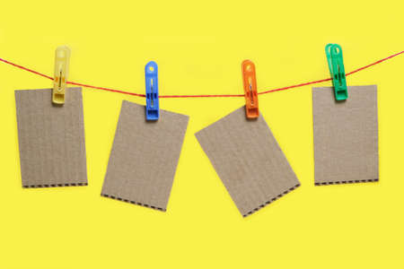 Cardboard cards are hung on clothespins on yellow background.Template for inscriptionの写真素材