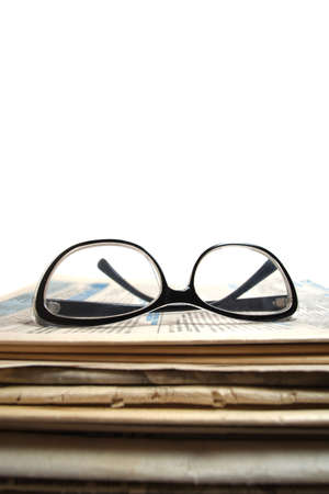 Stack of old newspapers and reading glasses on a white background